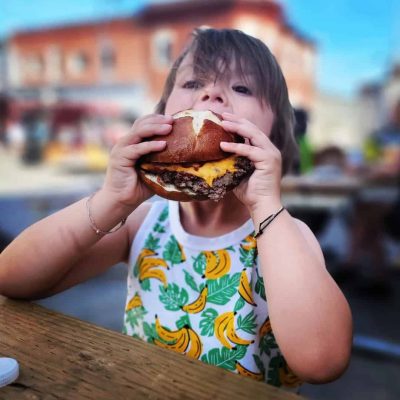 Kid eating a Cheeseburger at the Incredible Edibles Festival